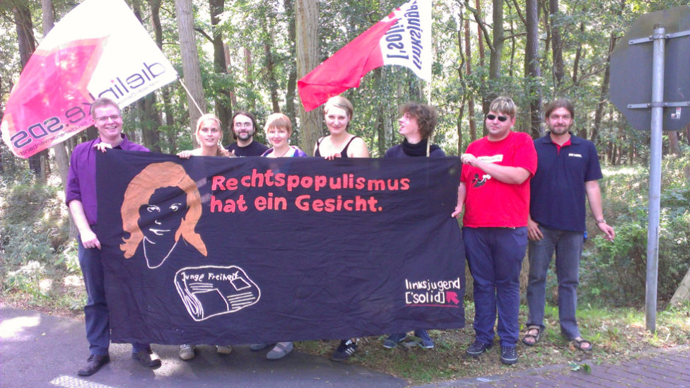 Gruppenfoto mit Fahnen von Linksjugend ['solid] und einem Transparent mit der Aufschrift: "Rechtspopulismus hat ein Gesicht"