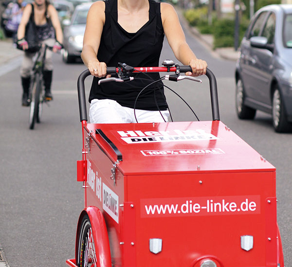 Diana Golze fährt mit einem Lastenfahrrad, auf dem das Logo der LINKEN zu erkennen ist