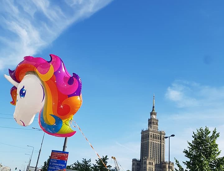Menschen mit Regenbogen-Fahnen und einem Einhorn-Luftballon vor dem Kulturpalast in Warschau