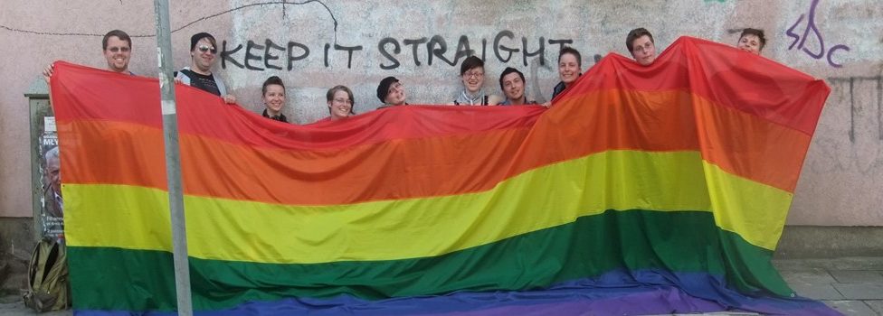 Mitglieder der LAG Queer mit einer überdimensionalen Regenbogen-Flagge