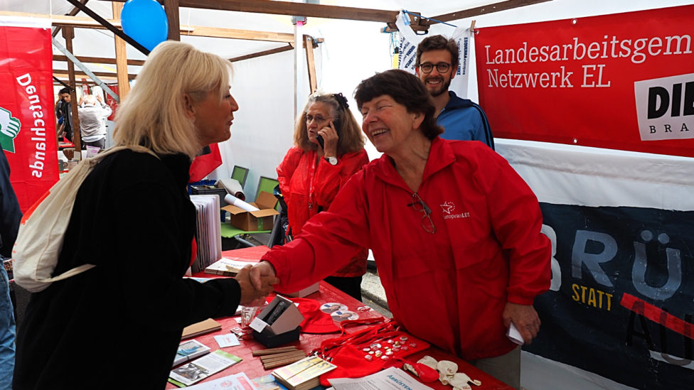 Dagmar Enkelmann steht an einem Infostand, auf dem Zeitungen liegen