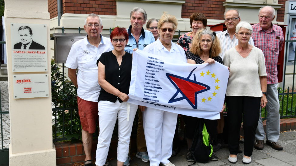 Die Mitglieder der LAG Netzwerk EL stehen vor dem Lothar-Bisky-Haus in Potsdam und halten eine Fahne mit dem Logo der Europäischen Linken