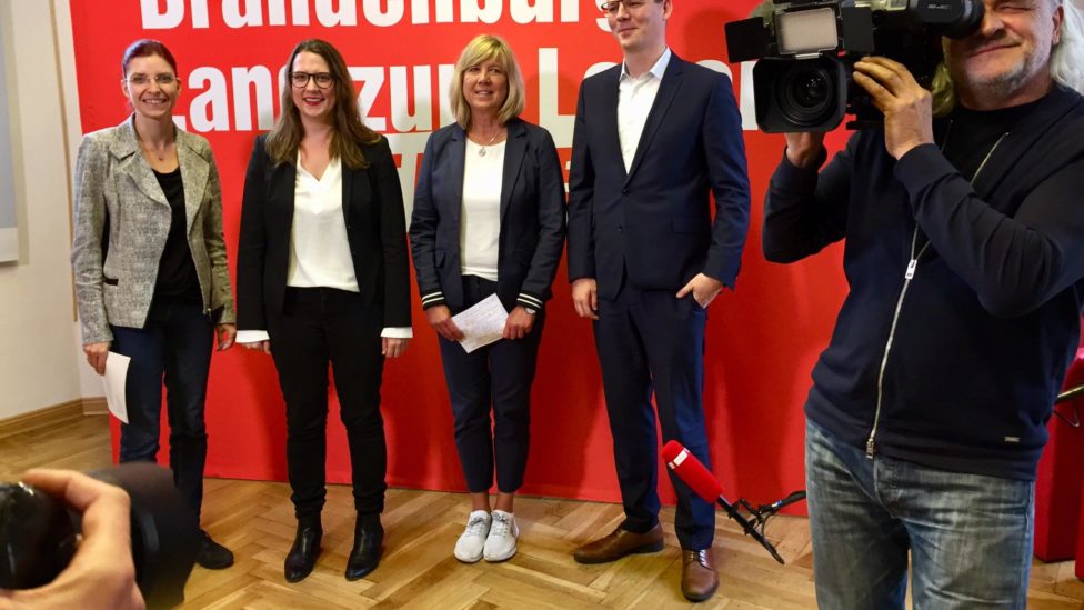Diana Golze, Anja Mayer, Kathrin Dannenberg und Sebastian Walter stehen vor einer Präsentationswand mit der Aufschrift: Brandenburg, Land zum Leben