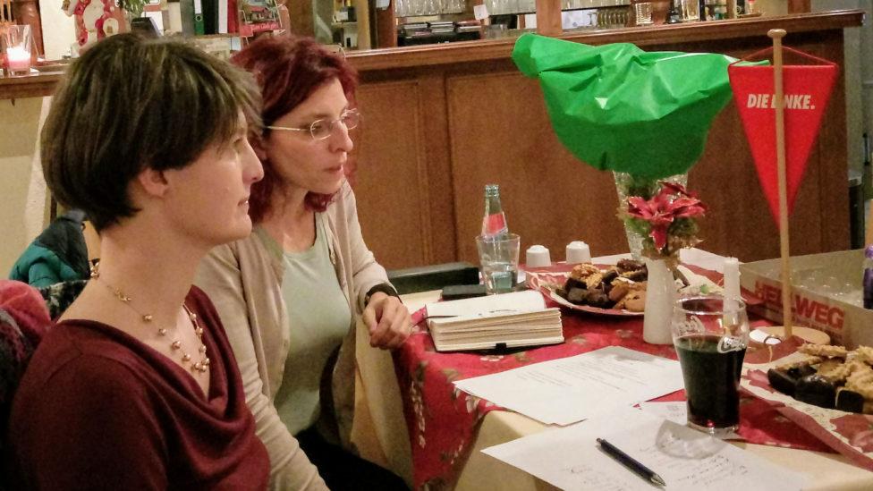 Monika von der Lippe und Diana Golze sitzen an einem Tisch mit Unterlagen und Gebäcktellern