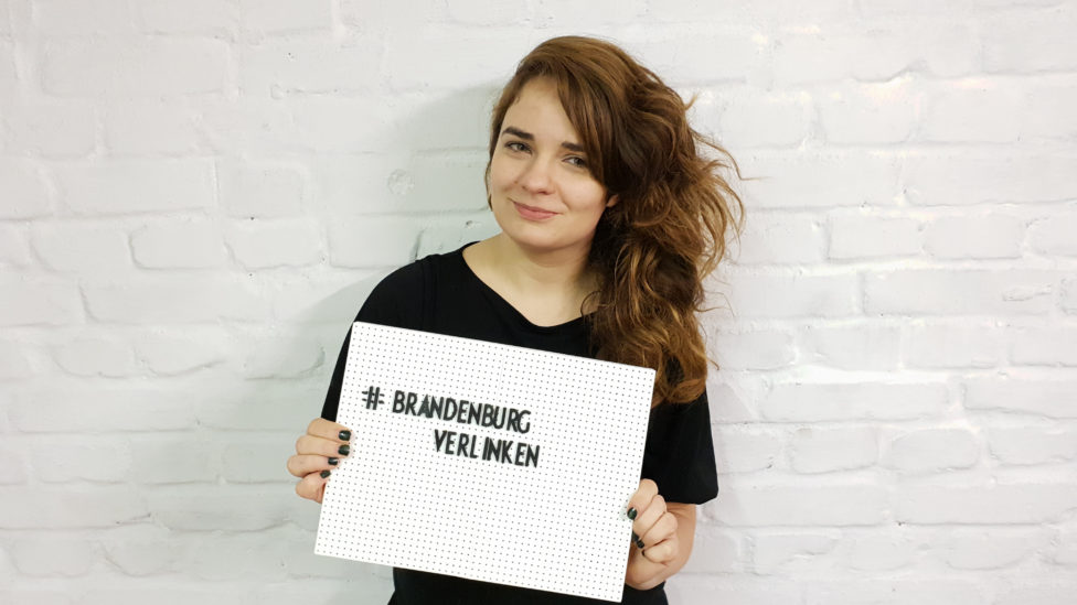 Claudia Sprengel hält ein Schild, auf dem "Brandenburg verlinken" steht