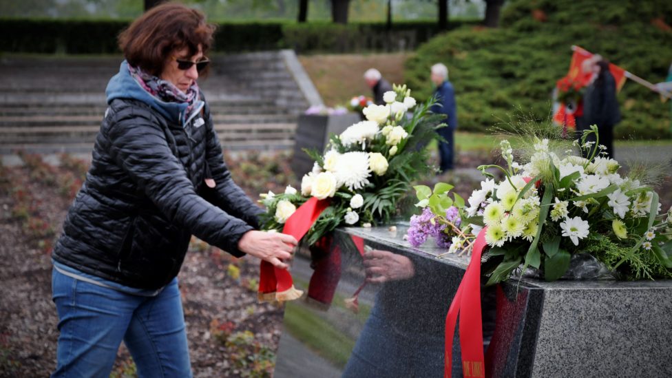 Claudia Kirchhoff legt ein Blumengesteck mit Gedenkschleife nieder