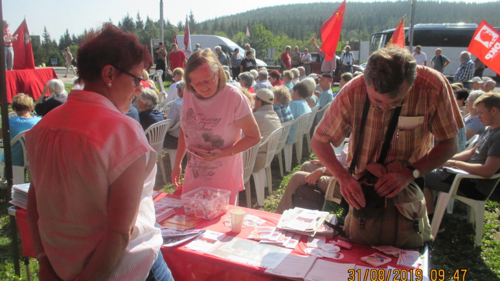 Infostand mit Materialien und Veranstaltungspublikum