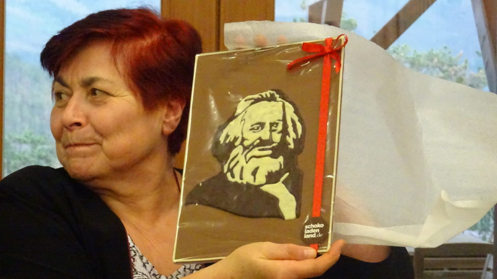 Eine Frau hält ein Bildnis von Karl Marx aus Schokolade in die Höhe