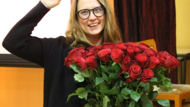 Anja Mayer mit einem Strauß roter Rosen, eine Faust in die Luft gestreckt