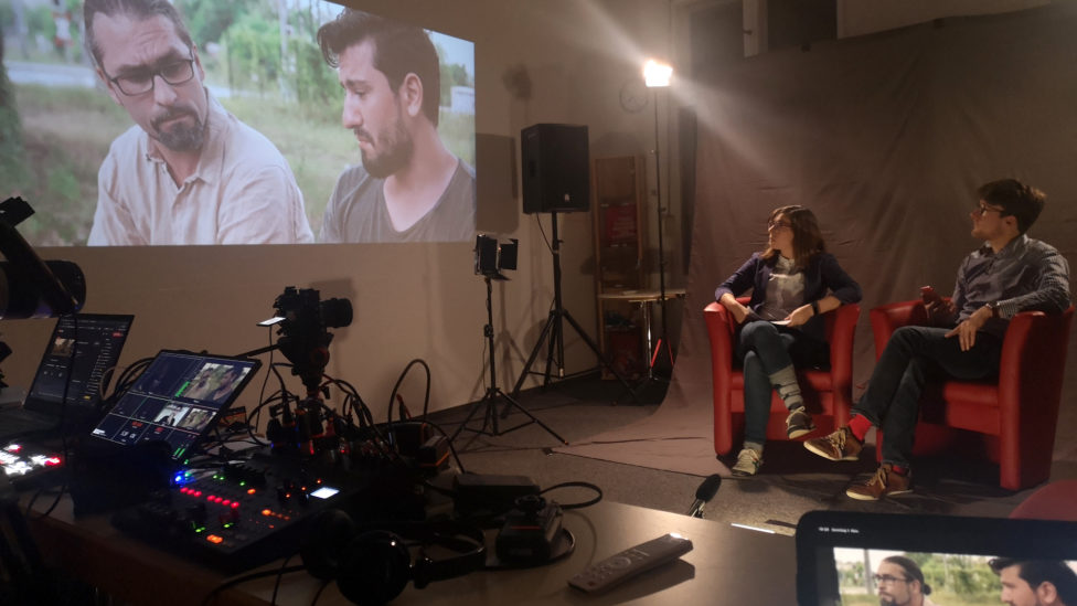 Filmset mit Scheinwerfern, Kamera und dem Film, der per Beamer an die Wand geworfen wird