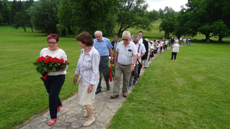 Teilnehmer der Gedenkveranstaltung in Lidice, Monika Schömmel trägt ein rotes Blumengebinde
