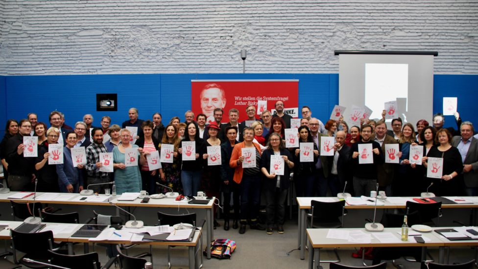 Gruppenfoto der Abgeordneten mit roten Handabdrücken auf Papier