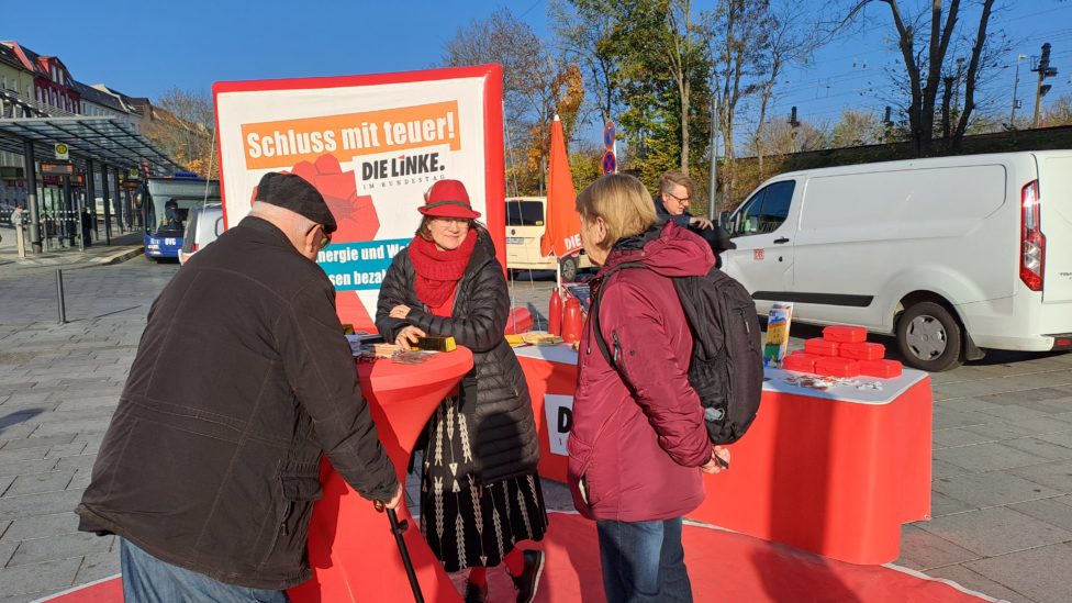 Anke Domscheit-Berg steht auf einem Platz im Freuen an einem Stehtisch mit roter Husse im Gespräch mit zwei weiteren Personen